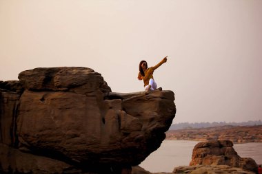 Kadınlar kayalık kayalıklarla nehrin doğada oturup.