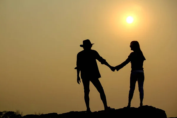 日落时分 女人和男人在岩石上剪影 — 图库照片