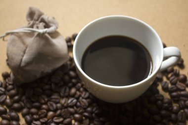 Black coffee in a white cup on coffee beans