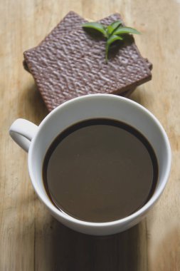 Beyaz cam ve gofret çikolata siyah kahve ahşap üzerine yerleştirilen.