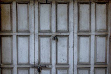 Eski gri ahşap kapı kilitliydi.