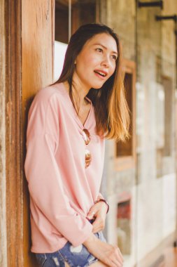 Ahşap bir kapı karşı bekleyen bir pembe gömlek giyen bir kadın.