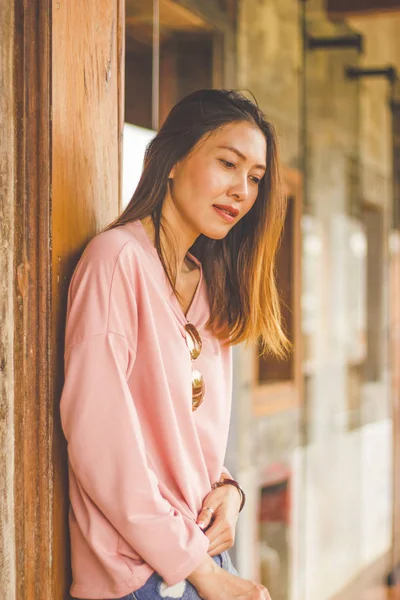 Ahşap bir kapı karşı bekleyen bir pembe gömlek giyen bir kadın.