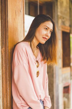 Ahşap bir kapı karşı bekleyen bir pembe gömlek giyen bir kadın.