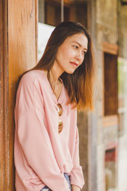 Ahşap bir kapı karşı bekleyen bir pembe gömlek giyen bir kadın.