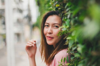 Kadın ayakta yaslanmış bir duvar kaplama yaprak yeşil.