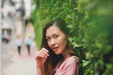 Kadın ayakta yaslanmış bir duvar kaplama yaprak yeşil.