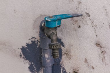 Eski mavi musluk üzerinde beyaz bir duvar olduğunu.