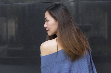 Gri granit duvara karşı duran genç bir kadın