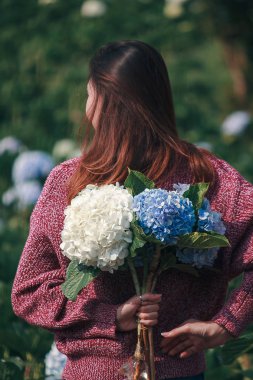 Ortanca bahçede kırmızı gömlek giyen ve eğlenen bir kadın.