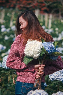 Ortanca bahçede kırmızı gömlek giyen ve eğlenen bir kadın.