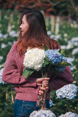 Ortanca bahçede kırmızı gömlek giyen ve eğlenen bir kadın.