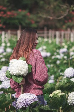 Ortanca bahçede kırmızı gömlek giyen ve eğlenen bir kadın.