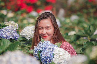 Ortanca bahçede kırmızı gömlek giyen ve eğlenen bir kadın.