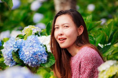 Ortanca bahçede kırmızı gömlek giyen ve eğlenen bir kadın.