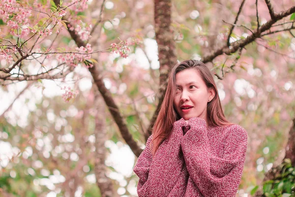站在绽放着粉色花朵的树下的女人 冬天美丽极了 — 图库照片