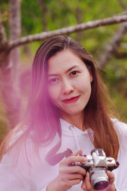 Women are smiling and holding a camera with pink flowers.