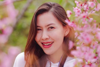 Women are smiling with pink flowers.