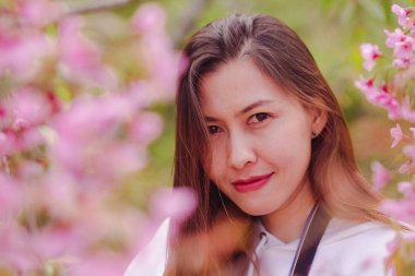 Women are smiling with pink flowers.