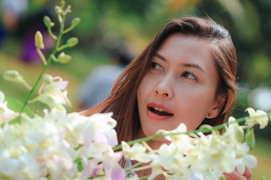 Genç kadının önünde beyaz orkideler var..