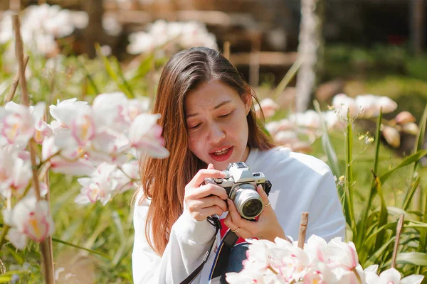 ピンク色の蘭の花の写真を撮る女性 — ストック写真