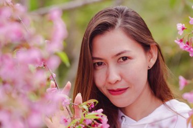 Women are smiling with pink flowers.