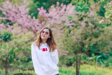 Woman standing on the lawn Has a pink tree on the back