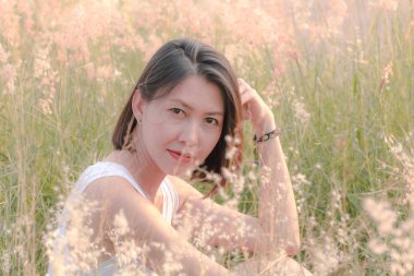 Çim tarlasında oturan kadın Gün batımının ışığıyla