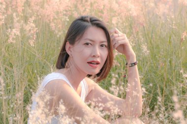 Çim tarlasında oturan kadın Gün batımının ışığıyla