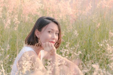 Çim tarlasında oturan kadın Gün batımının ışığıyla