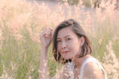 Çim tarlasında oturan kadın Gün batımının ışığıyla