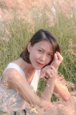 Çim tarlasında oturan kadın Gün batımının ışığıyla