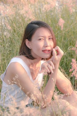 Çim tarlasında oturan kadın Gün batımının ışığıyla