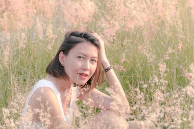 Çim tarlasında oturan kadın Gün batımının ışığıyla