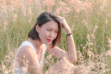 Çim tarlasında oturan kadın Gün batımının ışığıyla