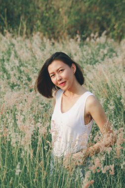 Çim tarlasında oturan bir kadın Mutlu bir gülümseme ve sallanan saçlarla