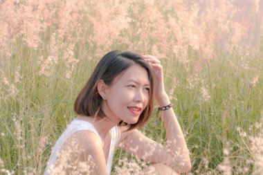 Çim tarlasında oturan kadın Gün batımının ışığıyla