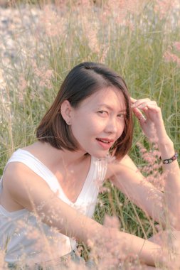 Çim tarlasında oturan kadın Gün batımının ışığıyla