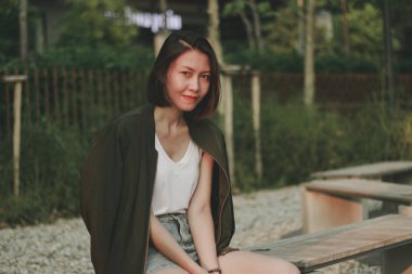 Yeşil gömlekli kadınlar parkta bir sandalyede oturan