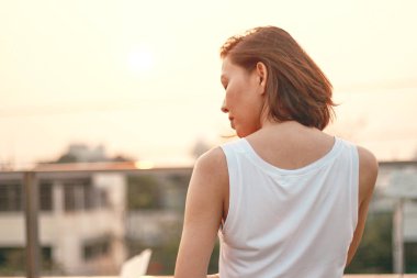 Gün batımında duran kadının arkası