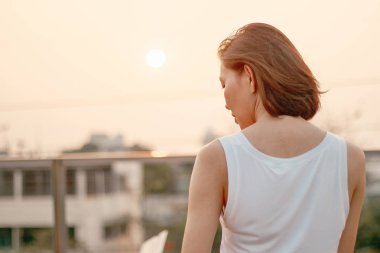 Gün batımında duran kadının arkası