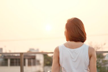 Gün batımında duran kadının arkası