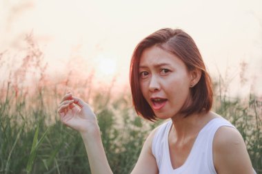 Çim tarlasında oturan kadın. Arka plan günbatımı ışığı.