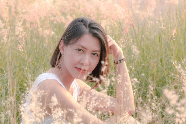 Çim tarlasında oturan kadın Gün batımının ışığıyla