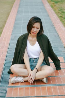 Yeşil gömlekkadın çim üzerinde oturan ve seyir