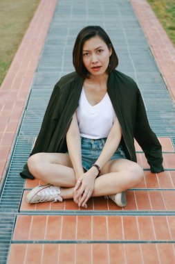 Yeşil gömlekkadın çim üzerinde oturan ve seyir