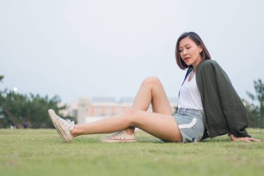 Çimlerin üzerinde oturan yeşil kadın.