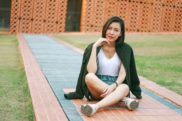 Yeşil gömlekkadın çim üzerinde oturan ve seyir