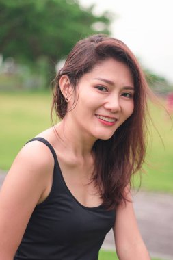 Kadın parkta oturdu ve sevinçle gülümsedi.