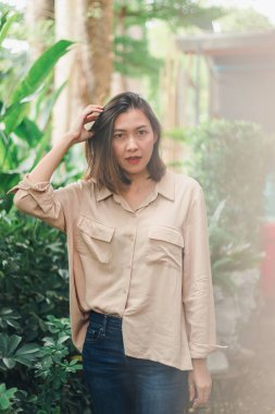 Bahçede poz veren kahverengi gömlek giyen kadınlar